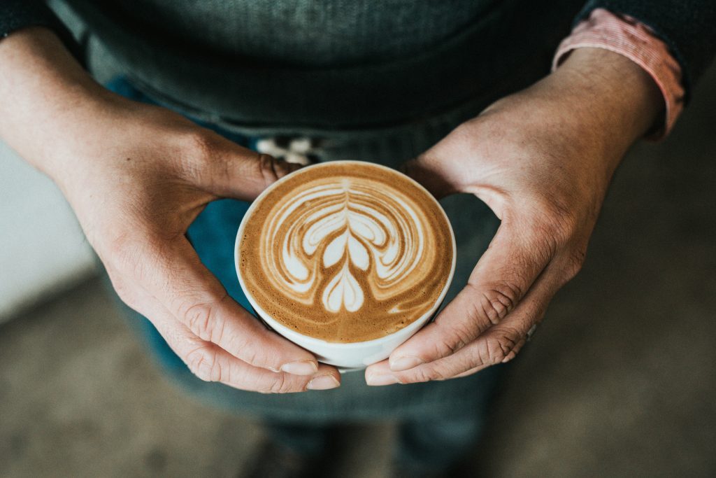 Barista holding a cup of latte with heart-shaped art