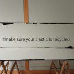 Sign on a workbench displaying the hashtag “#make sure your plastic is recycled”