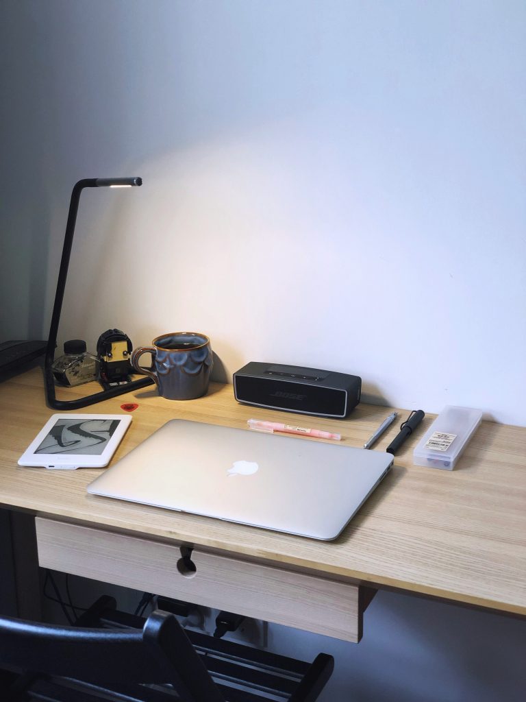 Minimalist study desk with closed laptop, tablet, lamp, pens, and coffee mug ready for a focused learning session