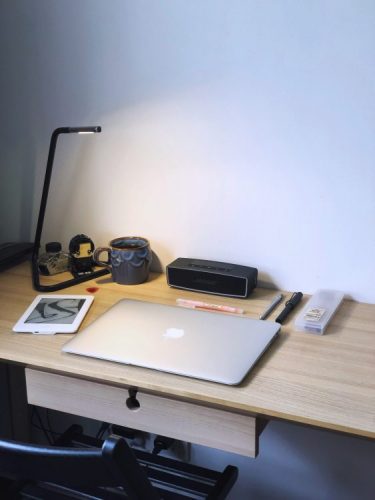 Minimalist study desk with closed laptop, tablet, lamp, pens, and coffee mug ready for a focused learning session